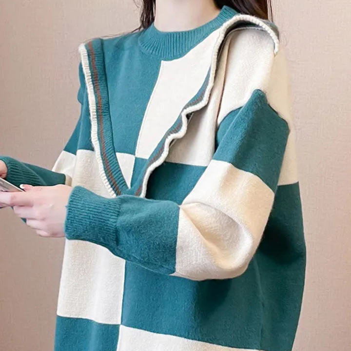 Vrouw in oversized geruite trui met blauw-witte blokken en ruffle detail, houdt smartphone vast. Modieuze dameskleding, trendy herfstoutfit.
