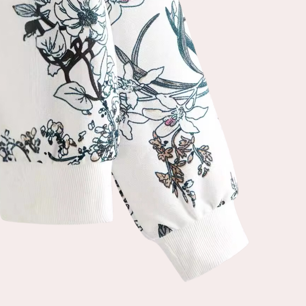 Witte blouse met bloemenprint, lange mouwen, elegante zwarte en blauwe bloemenmotieven, modieuze dameskleding, casual en stijlvol design.