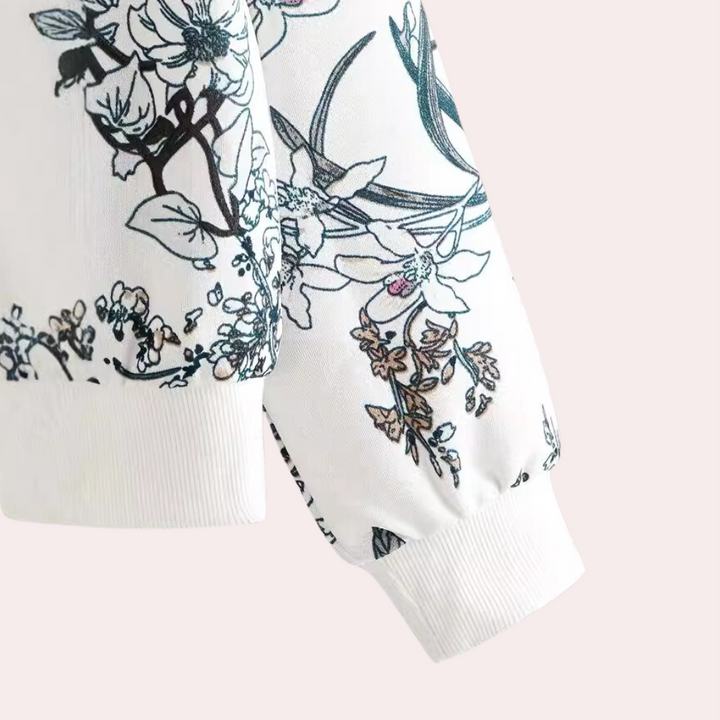 Witte blouse met bloemenprint, lange mouwen, elegante zwarte en blauwe bloemenmotieven, modieuze dameskleding, casual en stijlvol design.