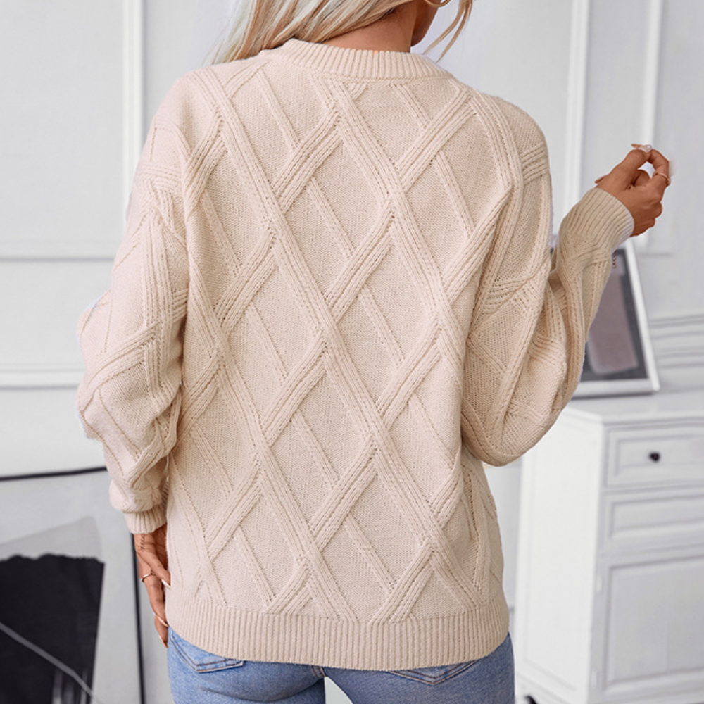 Beige gebreide trui met ruitpatroon, gedragen door een persoon, tegen een lichte achtergrond. Modieuze dameskleding, herfst-winter stijl.