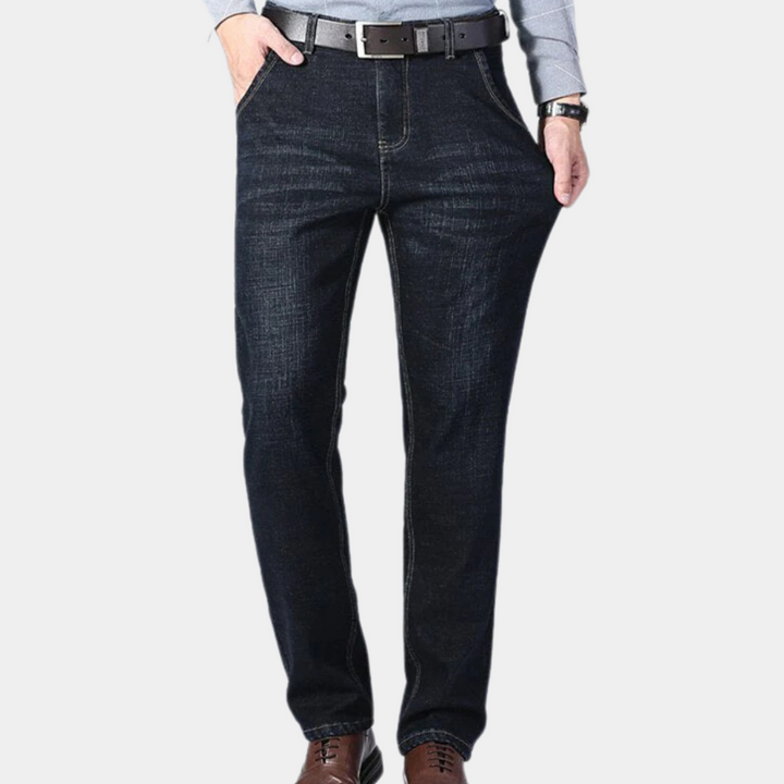 Donkerblauwe herenjeans met rechte pijpen, bruine leren riem en bruine schoenen. Casual herenkleding, comfortabele pasvorm, modieuze spijkerbroek.