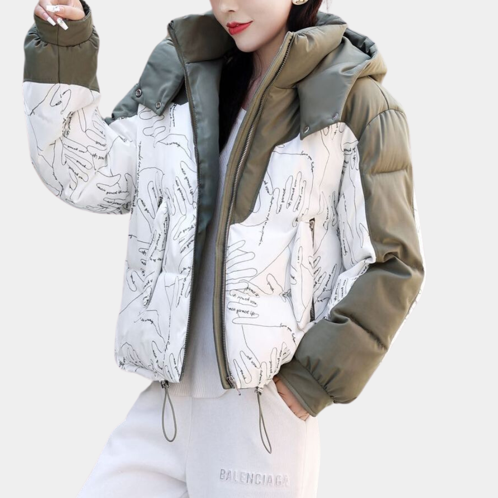 Vrouw in stijlvolle winterjas met handafdrukken, olijfgroene mouwen en capuchon, gecombineerd met grijze joggingbroek. Trendy wintermode.