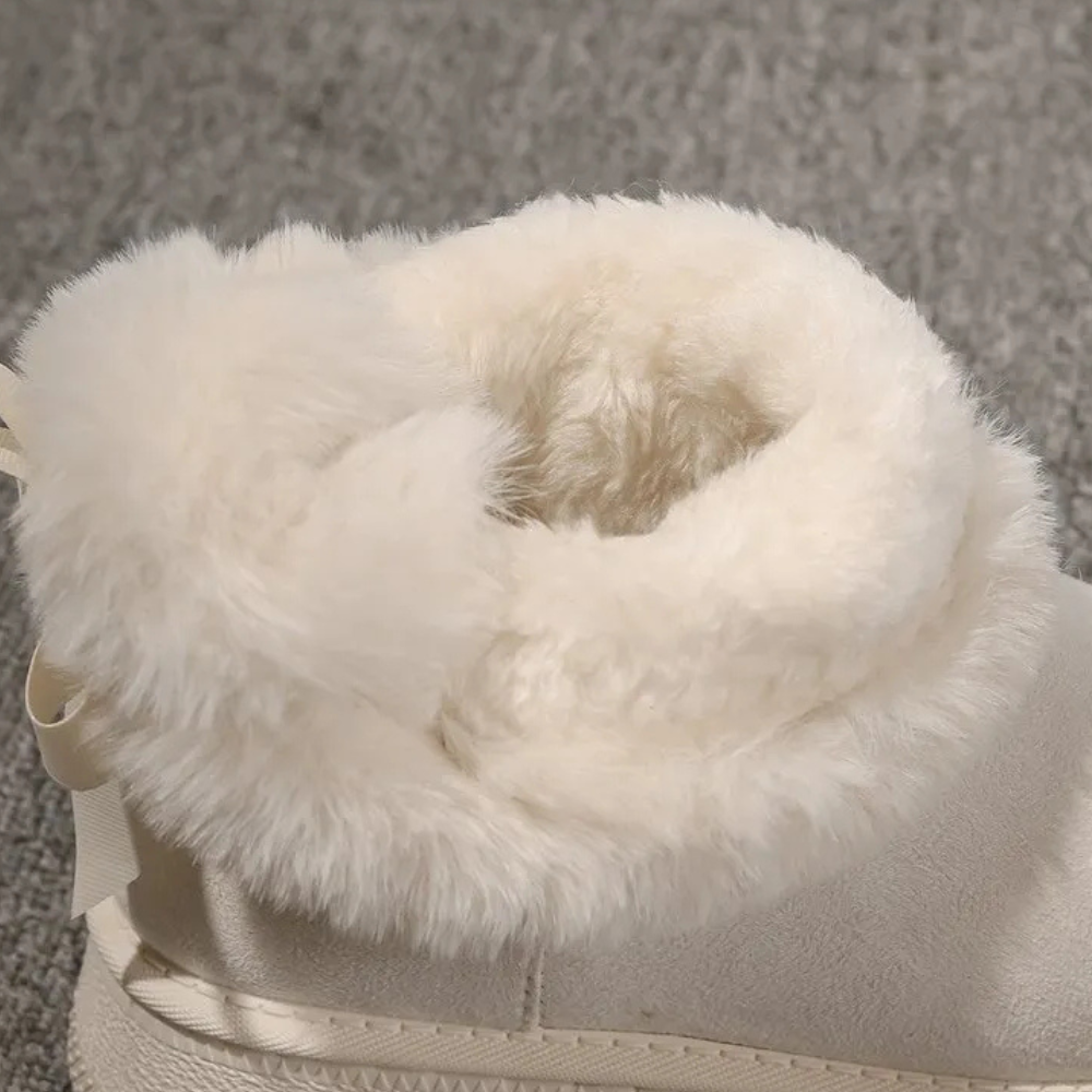 Witte bontgevoerde laars op grijze achtergrond, winterlaars met warme voering, comfortabele damesmode, trendy schoeisel voor koude seizoenen.