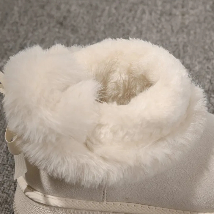 Witte bontgevoerde laars op grijze achtergrond, winterlaars met warme voering, comfortabele damesmode, trendy schoeisel voor koude seizoenen.