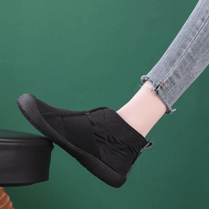 Zwarte enkellaars op groene achtergrond, gedragen met lichtblauwe jeans. Comfortabele, casual schoenen voor dagelijks gebruik. Mode, schoenen, casual stijl.