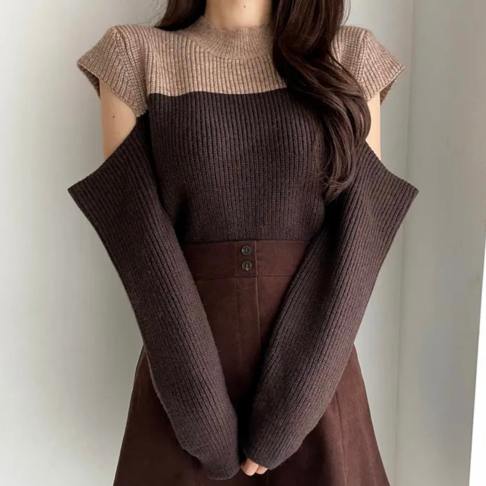 Vrouw in bruine, mouwloze trui met beige bovenkant en lange, losse mouwen, gecombineerd met een bruine rok. Modieuze herfstkleding.