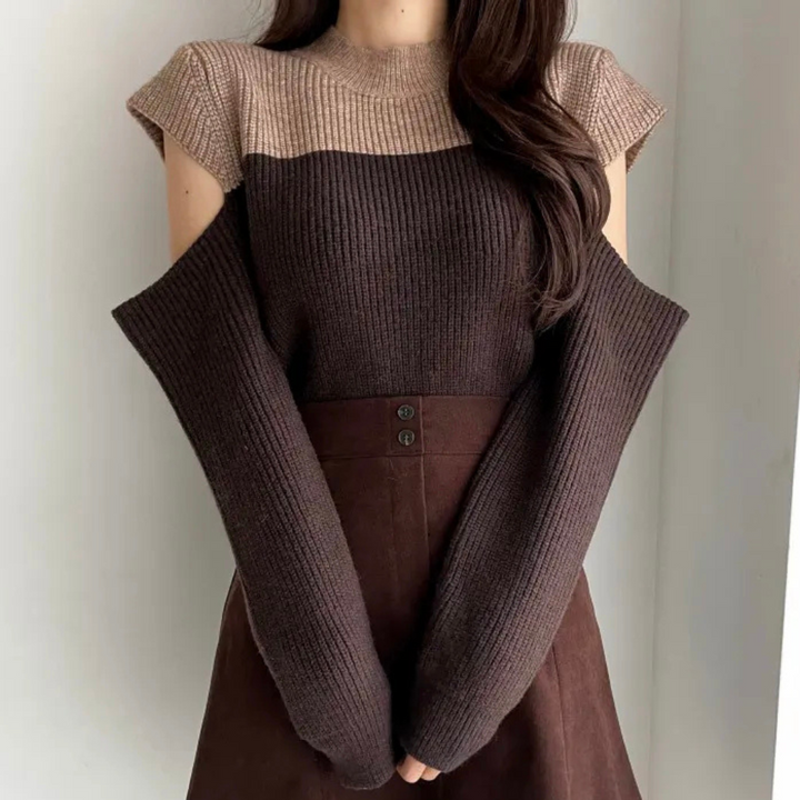Vrouw in bruine, mouwloze trui met beige bovenkant en lange, losse mouwen, gecombineerd met een bruine rok. Modieuze herfstkleding.