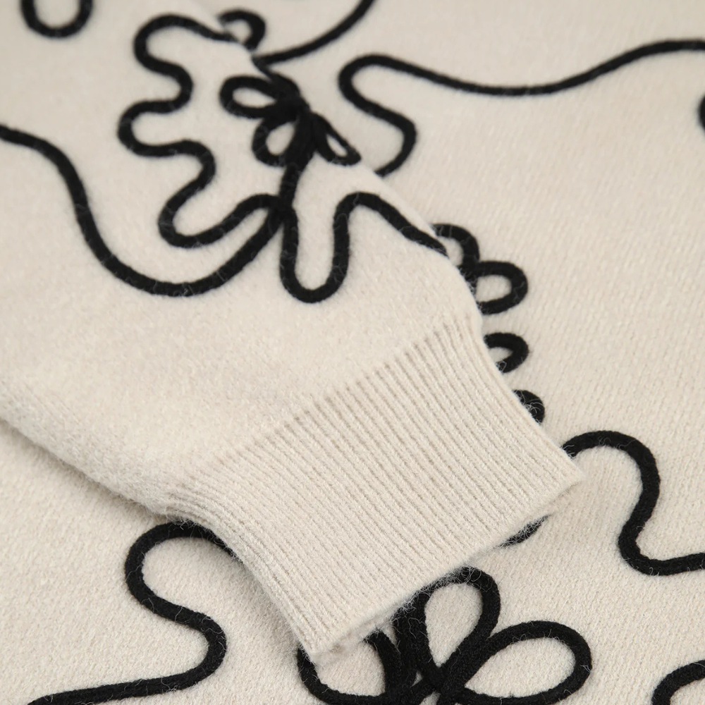 Crèmekleurige trui met zwarte abstracte lijnen, gebreide manchetten, moderne mode, comfortabele winterkleding, stijlvolle damestrui.