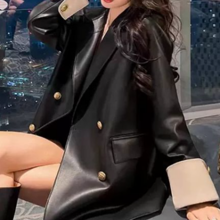 Vrouw in zwarte leren jas met gouden knopen, zittend op een bank. Modieuze outfit, trendy stijl, luxe uitstraling, moderne mode.