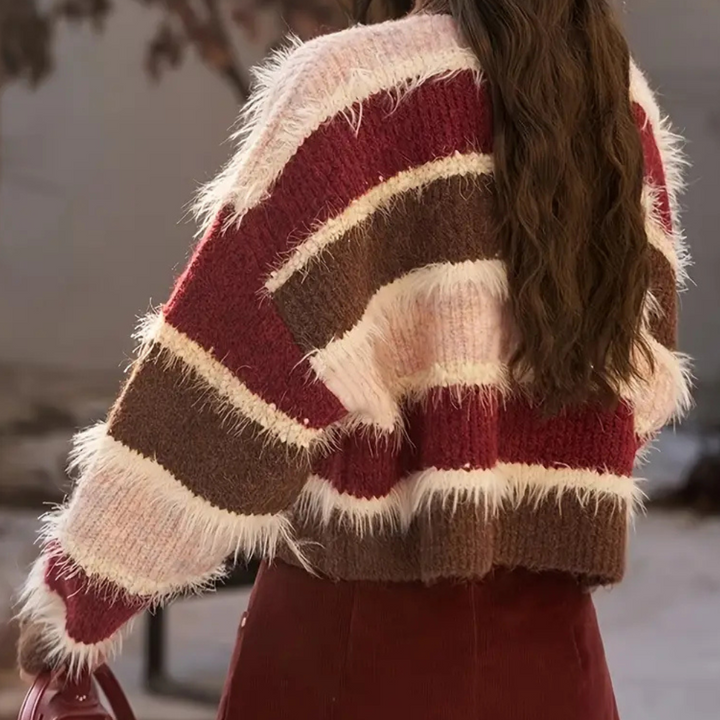 Vrouw in gebreide trui met rode, roze en bruine strepen en pluizige textuur, herfstmode, trendy dameskleding, buitenomgeving.