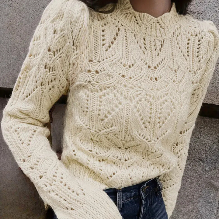 Beige gebreide trui met ingewikkeld patroon, lange mouwen en ronde hals, gedragen door model. Perfect voor herfstmode en casual outfits.