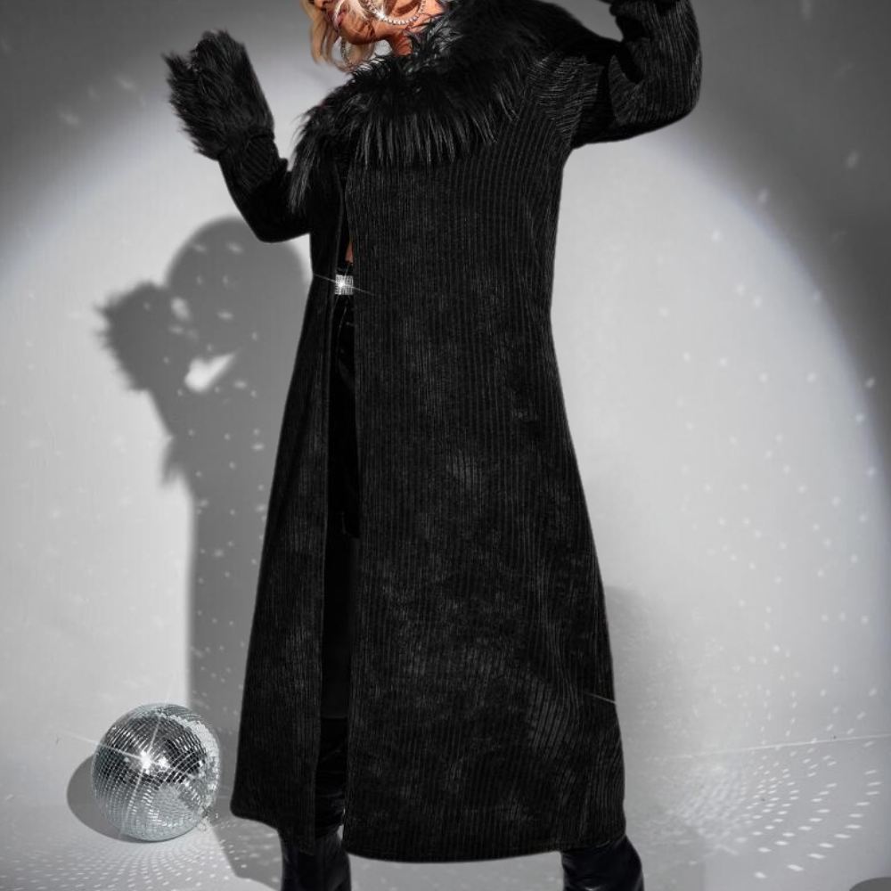 Zwarte lange jas met bontkraag en mouwen, gedragen door persoon met disco bal op de achtergrond. Modieuze winterkleding, trendy stijl.