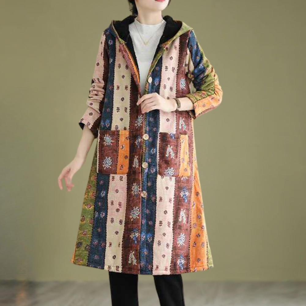 Vrouw draagt lange, kleurrijke boho-jas met etnisch patroon en capuchon, perfect voor herfstmode. Stijlvolle dameskleding, unieke bohemian look.