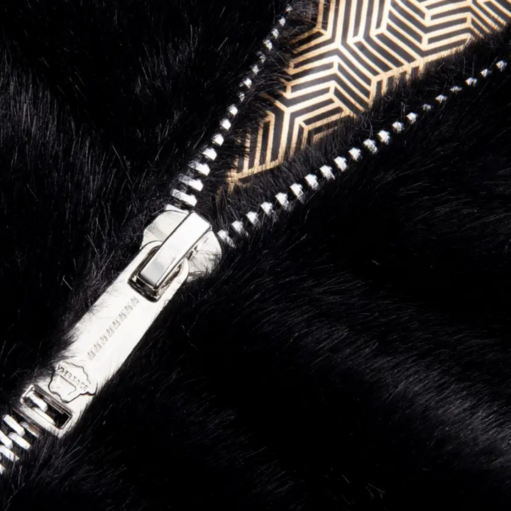 Zilveren ritssluiting op zwarte bontjas met geometrisch patroon. Luxe wintermode, hoogwaardige materialen, stijlvolle kledingaccessoires.