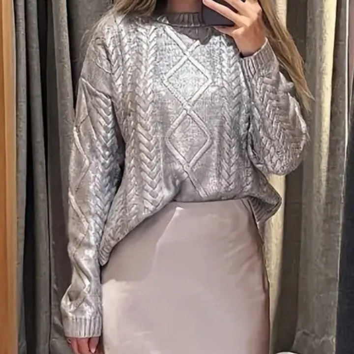 Grijze gebreide trui met kabelpatroon, gedragen door vrouw, gecombineerd met een lichtroze rok. Modieuze dameskleding, herfst/winter stijl.