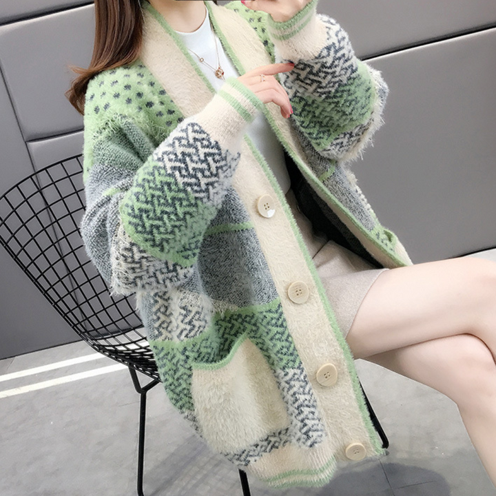 Vrouw draagt oversized gebreid vest met groene en beige patronen, knopen en zakken. Trendy herfstmode, comfortabele dameskleding.