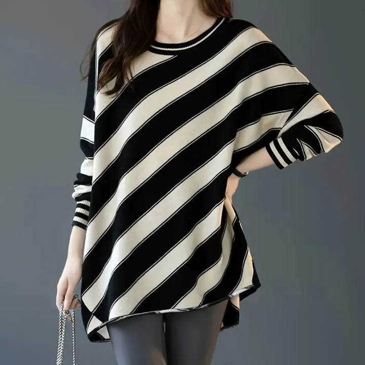 Vrouw draagt oversized zwart-wit gestreepte trui, modieuze dameskleding, casual stijl, comfortabele pasvorm, trendy herfstmode.