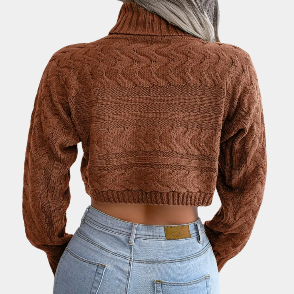 Bruine gebreide cropped trui met kabelpatroon, gedragen door model met lichtblond haar en blauwe jeans. Modieuze herfstkleding, damesmode.