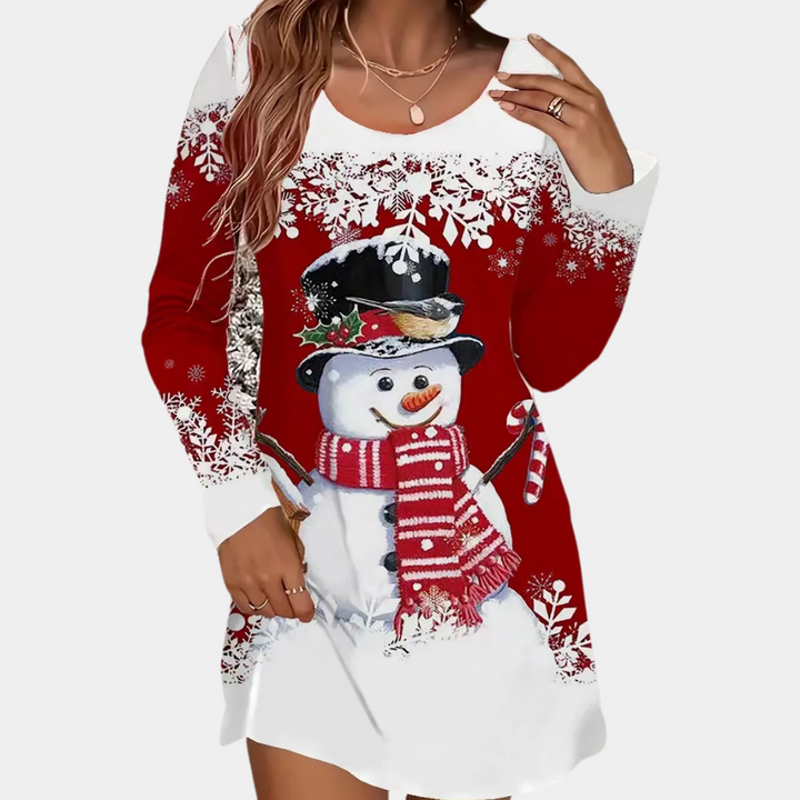 Vrouw draagt rode kerstjurk met sneeuwpopprint, witte sneeuwvlokken en rode sjaal. Perfect voor feestdagen, wintermode, casual kerstoutfit.