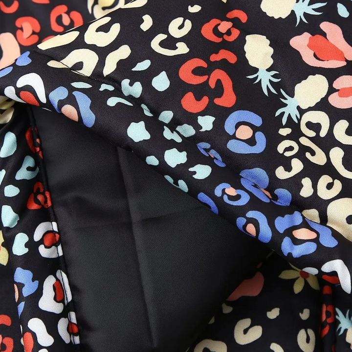Stof met kleurrijk luipaardprintpatroon op zwarte achtergrond, close-up. Ideaal voor modeontwerp, textiel, kleding en interieurdecoratie.