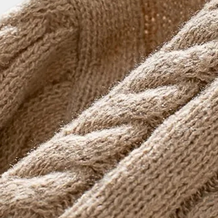 Beige gebreide trui met kabelpatroon, close-up. Zachte woltextuur, warme winterkleding, modieuze gebreide stof, comfortabele herentrui.