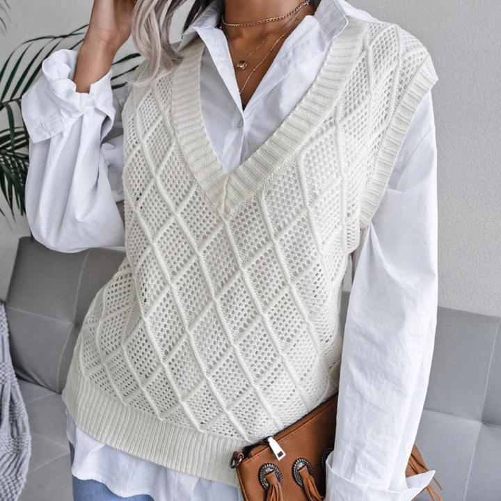 Vrouw draagt witte gebreide spencer over blouse, met bruine leren tas. Modieuze dameskleding, herfstoutfit, casual stijl, trendy modeaccessoires.