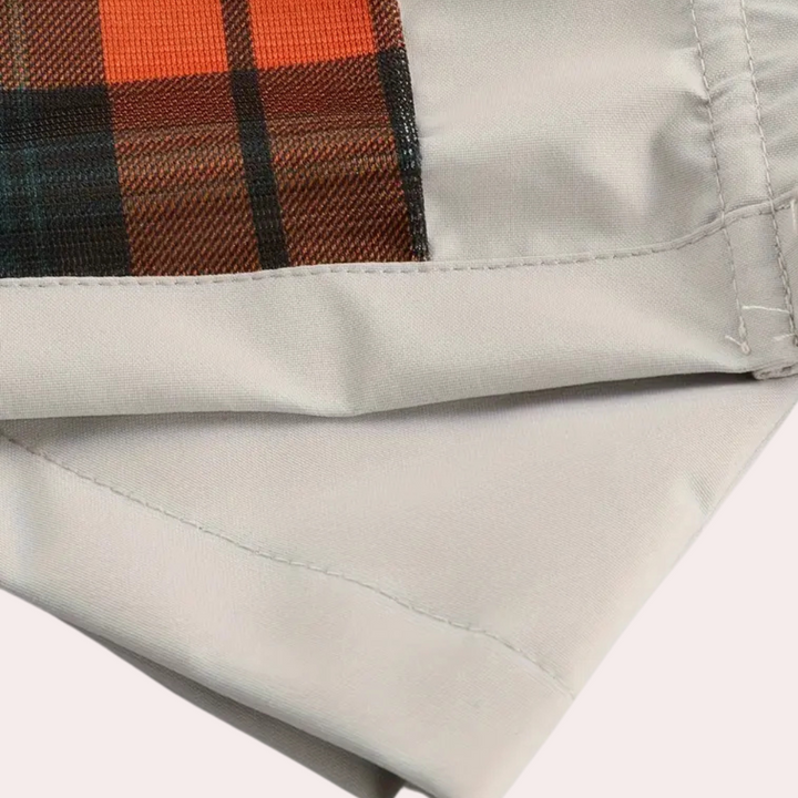 Grijze jas met oranje geruite voering, close-up. Modieuze herfstkleding, hoogwaardige stof, trendy design, warme jas voor heren en dames.