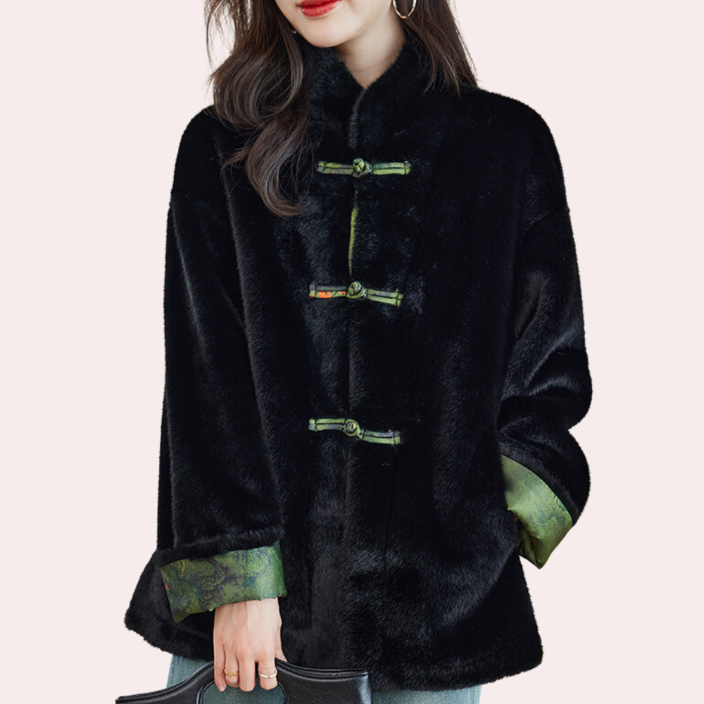 Vrouw in zwarte faux bontjas met groene accenten, stijlvolle wintermode, trendy dameskleding, elegante jas voor koude seizoenen.