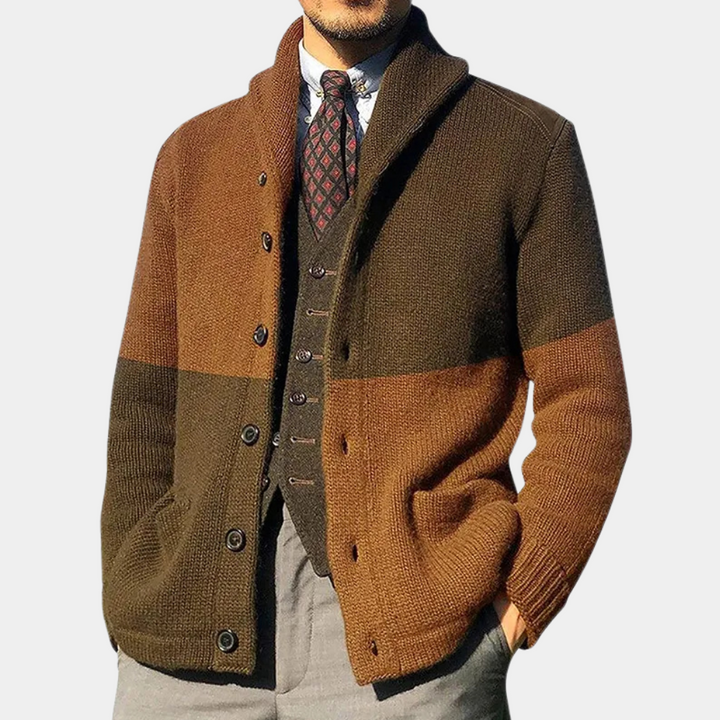 Man in bruine en olijfgroene gebreide cardigan met knopen, over een grijze gilet en geruite stropdas. Stijlvolle herenkleding, herfstmode.