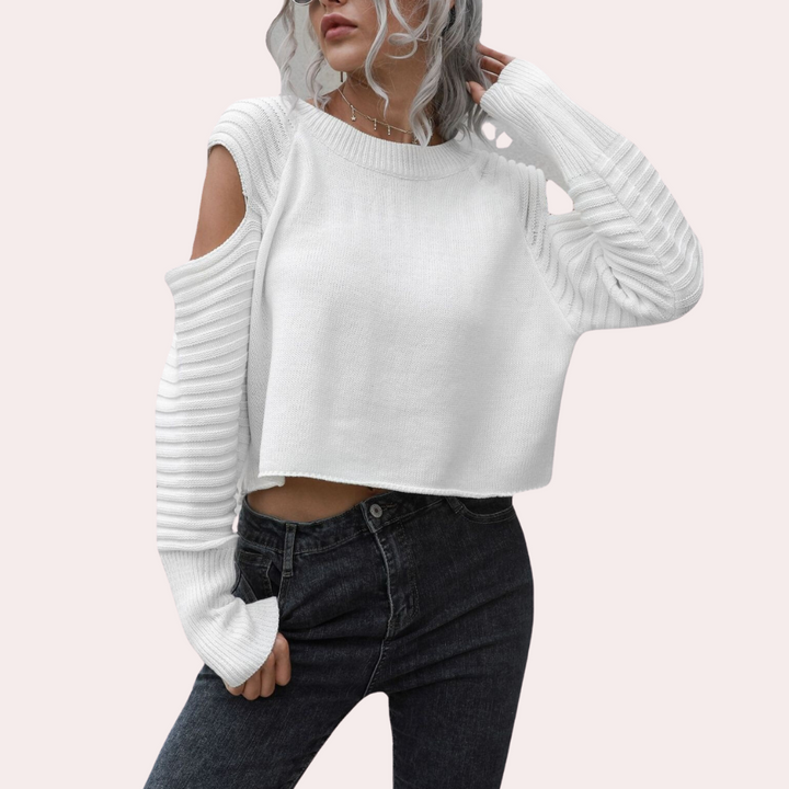 Vrouw in witte trui met open schouder en geribbelde mouwen, gecombineerd met donkere jeans. Modieuze dameskleding, casual stijl.
