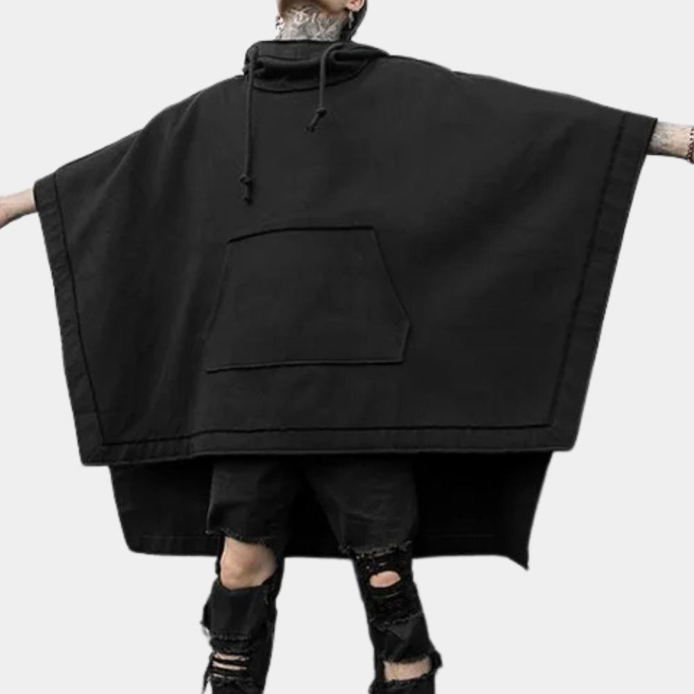 Zwarte oversized poncho met capuchon, grote zak en gescheurde zwarte jeans. Streetwear mode, unisex, casual stijl.