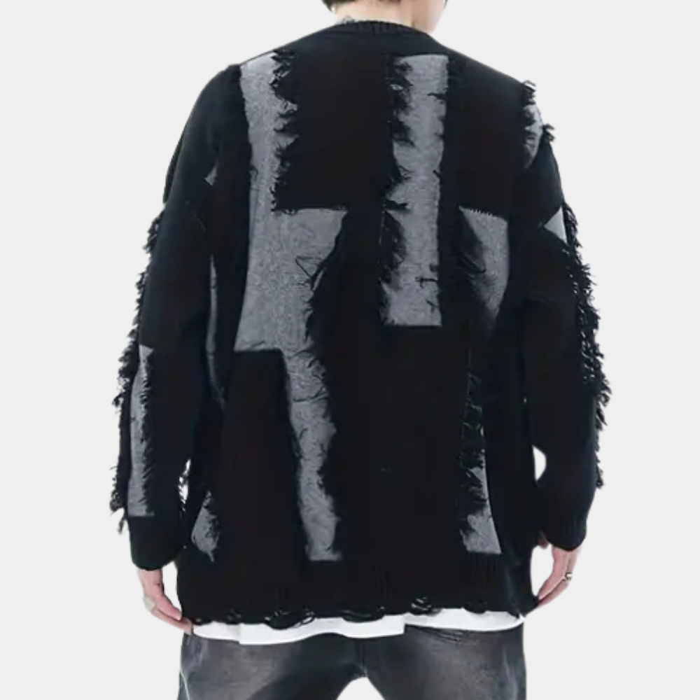 Zwarte oversized trui met grijze geometrische patronen en rafelige details, gedragen door een persoon. Trendy streetwear mode, unisex design.