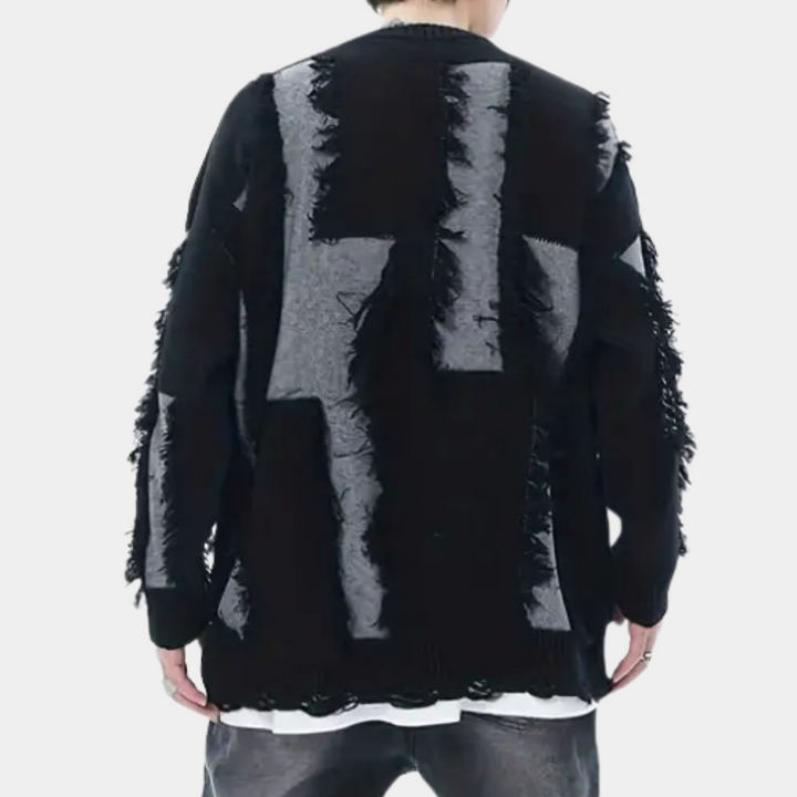Zwarte oversized trui met grijze geometrische patronen en rafelige details, gedragen door een persoon. Trendy streetwear mode, unisex design.