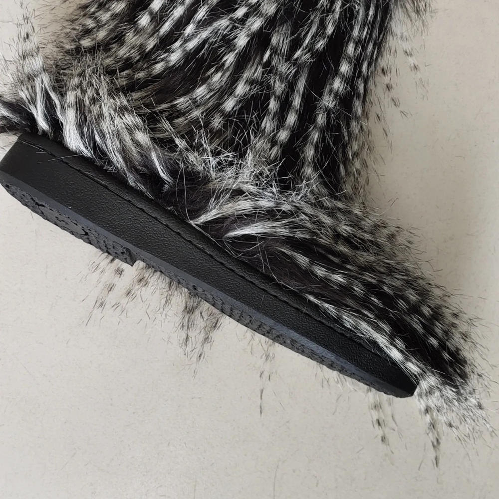 Zwart-witte bontlaars met dikke zool, modieuze winterlaars, synthetisch bont, trendy damesmode, warme winterkledingaccessoire.