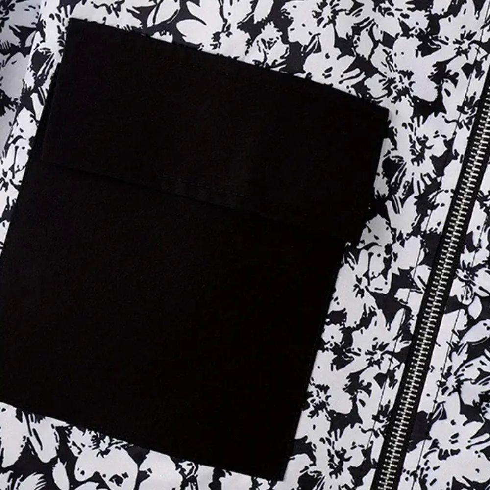 Zwart-witte bloemenjas met rits en zwarte zak. Modieuze dameskleding, trendy bloemenprint, stijlvolle jas voor dagelijks gebruik.