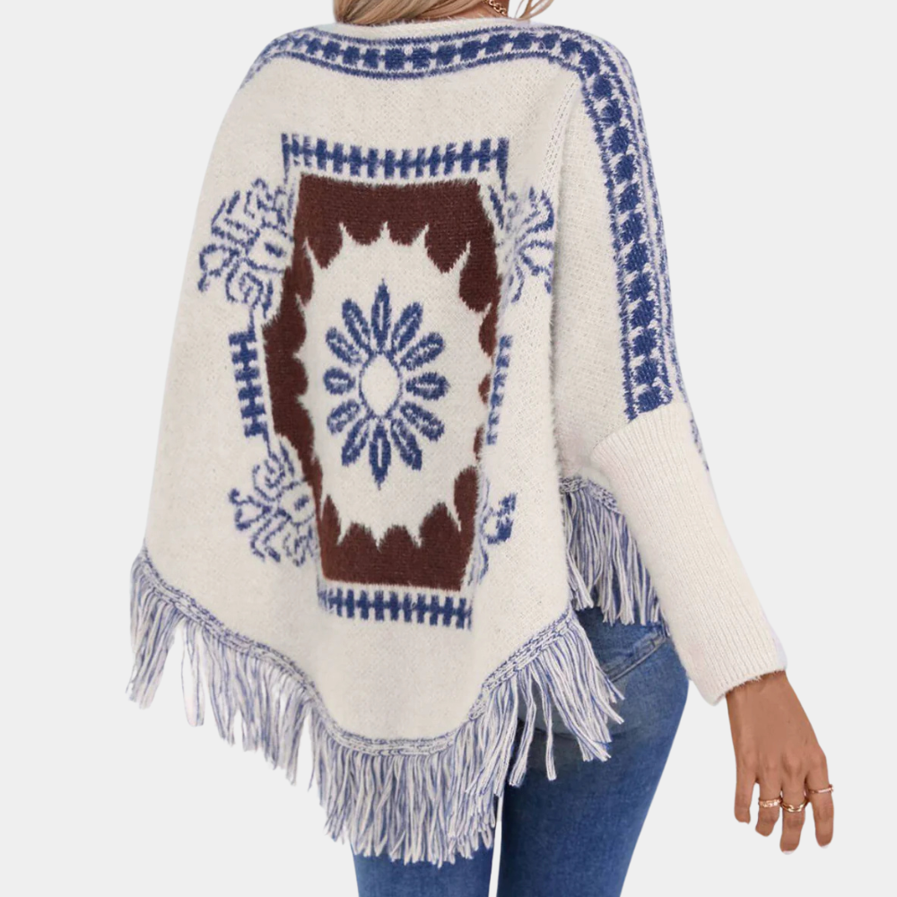 Vrouw draagt gebreide poncho met blauwe en bruine bloemenprint en franjes, casual mode, herfstkleding, bohemian stijl, comfortabele dameskleding.