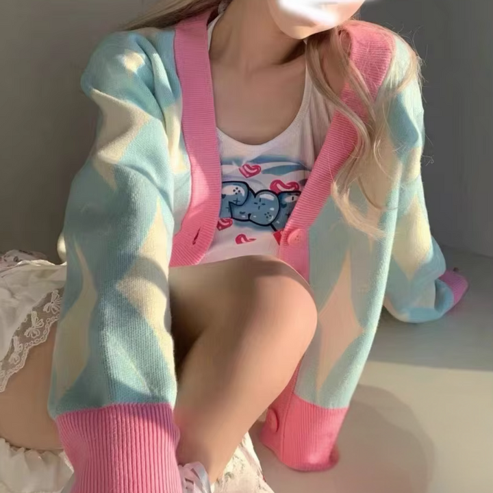 Vrouw in pastel gekleurde cardigan met geometrisch patroon, zittend in zonlicht. Trendy damesmode, casual lente outfit, zachte kleuren.