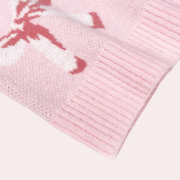 Roze gebreide trui met witte en rode abstracte print, close-up van de mouw. Zachte stof, modieuze dameskleding, comfortabele wintermode.