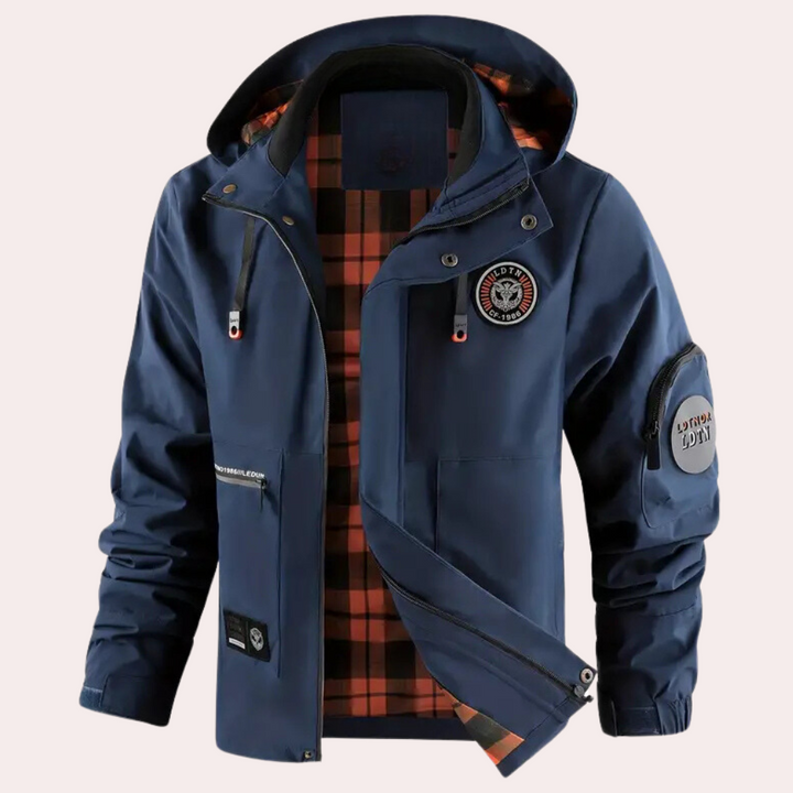 Donkerblauwe herenjas met capuchon, oranje geruite voering en meerdere zakken. Ideaal voor outdoor activiteiten. Waterdicht en windbestendig.