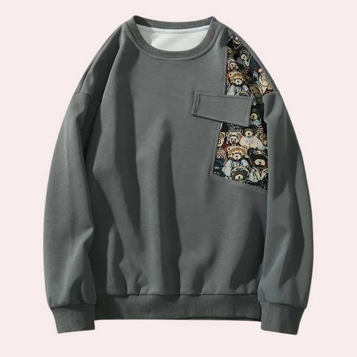 Grijze sweatshirt met unieke patchwork print op de borst, lange mouwen en ronde hals. Modieuze herentrui, casual streetwear stijl.