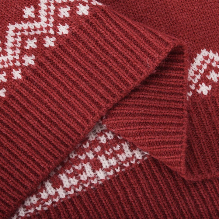 Rode gebreide trui met witte Noorse patronen, close-up textuur. Wintermode, warme kleding, Scandinavisch design.