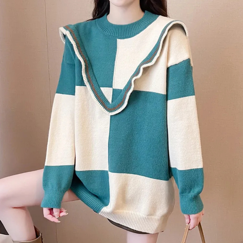 Vrouw draagt oversized geblokte trui in groen en beige met ruches. Modieuze dameskleding, herfst-winter stijl, comfortabele casual outfit.