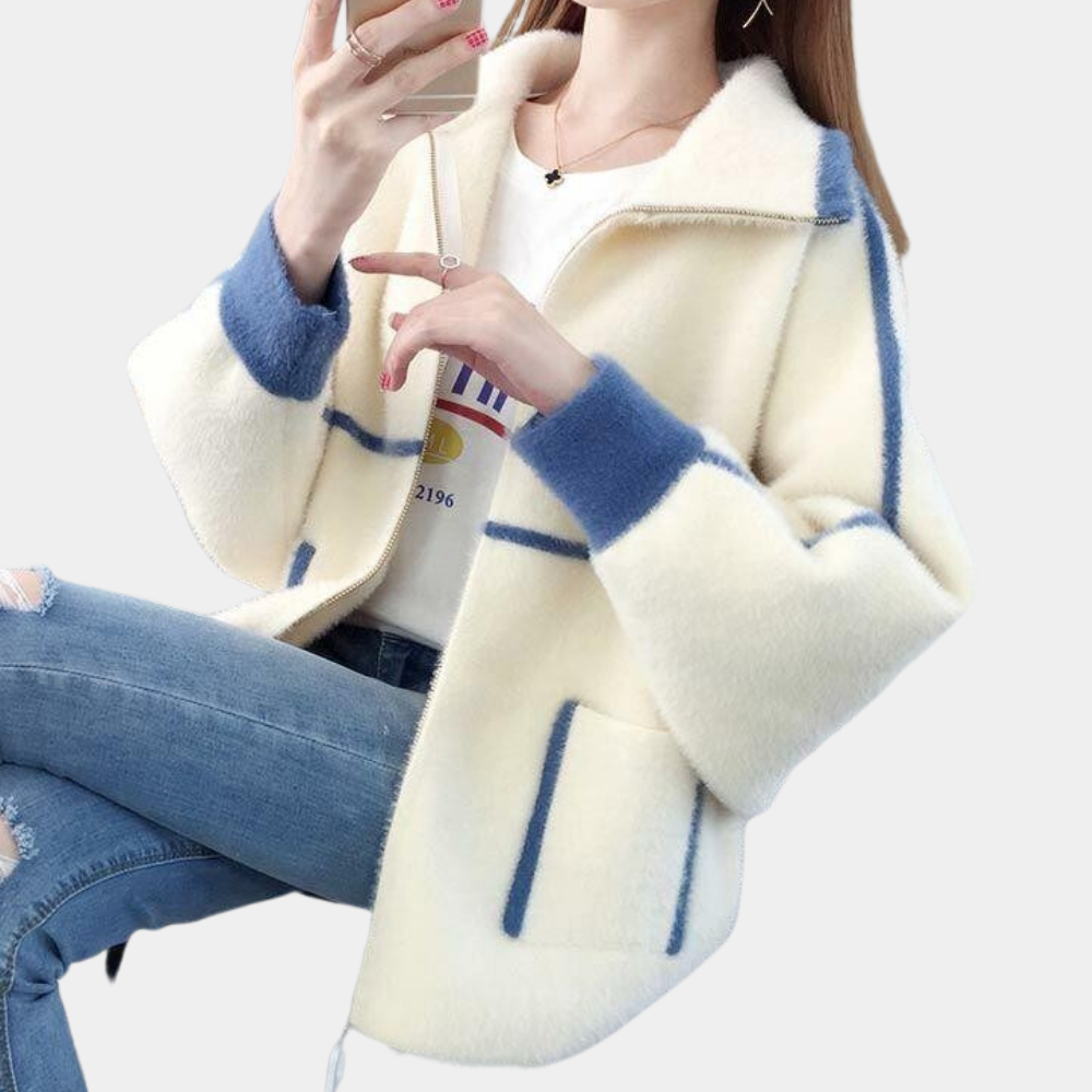 Vrouw draagt stijlvolle witte jas met blauwe accenten, gecombineerd met een casual jeans. Modieuze dameskleding, herfst-winter outfit.
