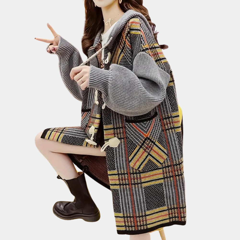 Vrouw in oversized geruite trui met grijze mouwen en capuchon, maakt V-teken. Modieuze herfstkleding, trendy streetwear stijl.