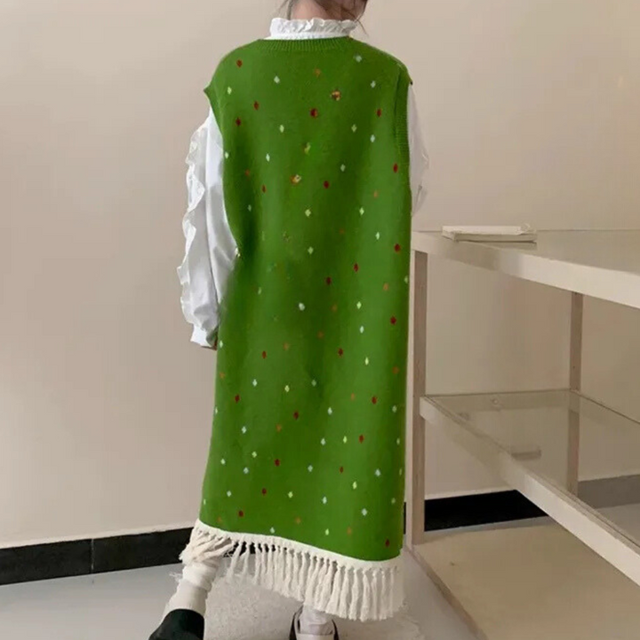 Groene gebreide jurk met kleurrijke stippen en franjes, gedragen door een persoon. Trendy wintermode, comfortabele en stijlvolle outfit.