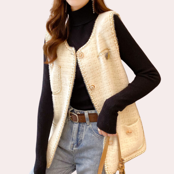 Damesmode: Elegante beige wollen gilet met knopen, gedragen over zwarte coltrui en spijkerbroek. Trendy herfstoutfit voor casual en chique gelegenheden.