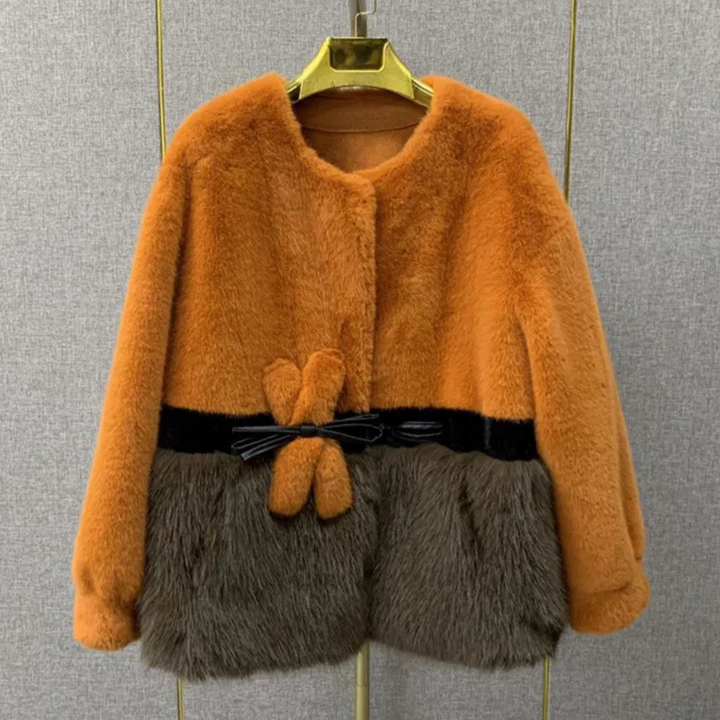 Oranje en bruine faux fur jas met strikdetail, hangend aan gouden hanger. Stijlvolle wintermode, warme damesjas, trendy design.