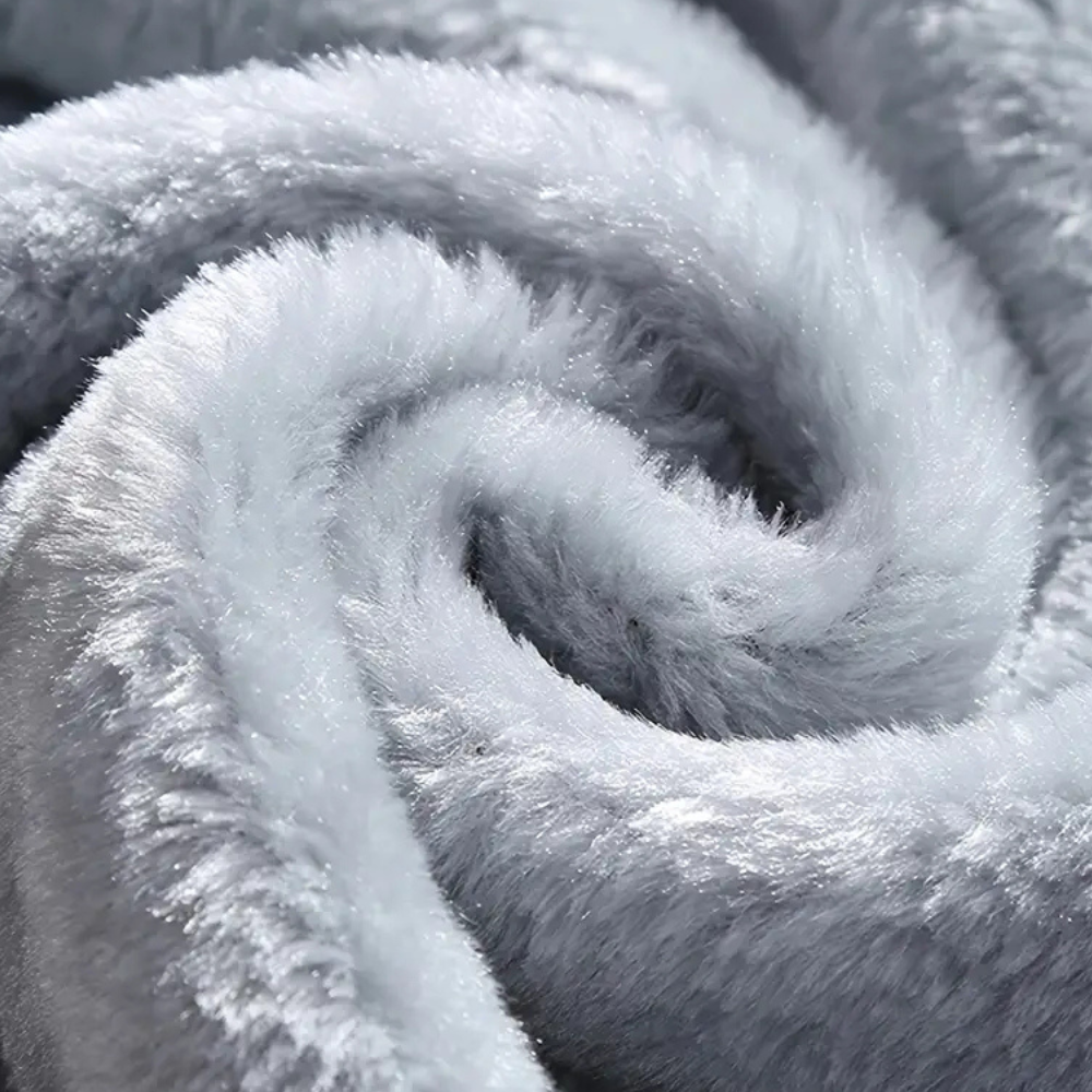 Zachte grijze pluche deken close-up, luxueus en warm, ideaal voor wintercomfort en interieurdecoratie. Perfect voor slaapkamer of woonkamer.