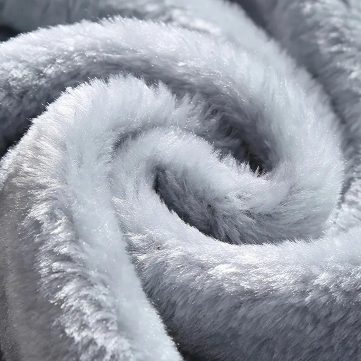 Zachte grijze pluche deken close-up, luxueus en warm, ideaal voor wintercomfort en interieurdecoratie. Perfect voor slaapkamer of woonkamer.