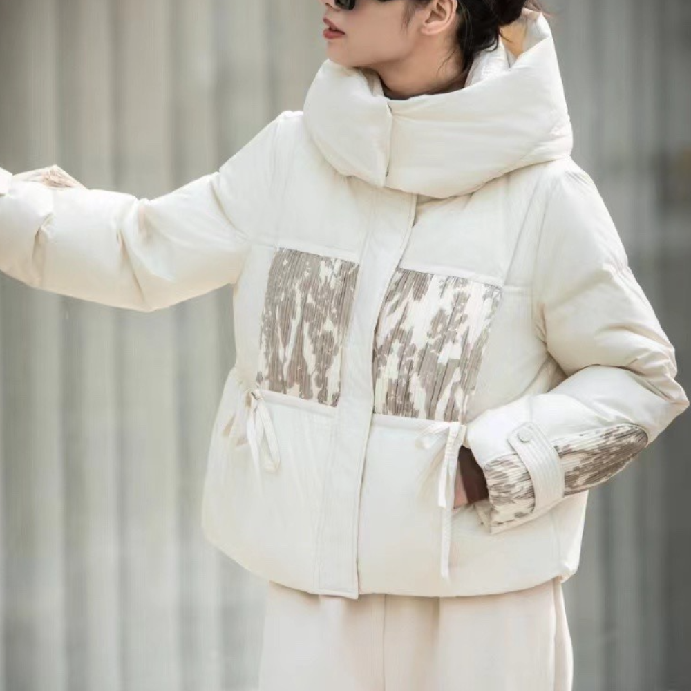 Vrouw in stijlvolle witte winterjas met hoge kraag en abstract patroon, modetrend, warme kleding, buitenkleding voor dames, wintermode.